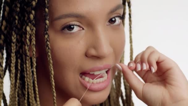Dientes femeninos africanos que florecen con el hilo dental sobre fondo blanco — Vídeos de Stock