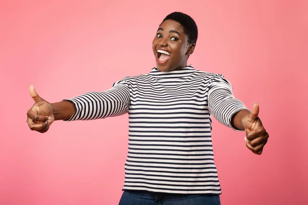 Vrolijke Plus Size Afrikaanse vrouw die duimen opzuigt over roze achtergrond — Stockfoto