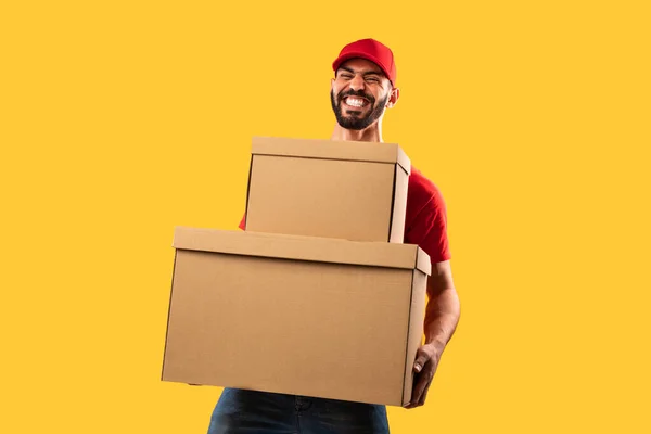 Funny Middle Eastern Courier Man Holding Heavy Parcels Over Yellow Background — Stok Foto
