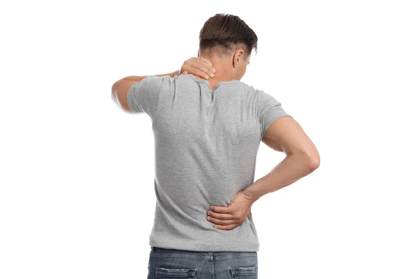 Молодой европейский мужчина, страдающий от мышечной боли, прижимает руку к спине и шее — стоковое фото