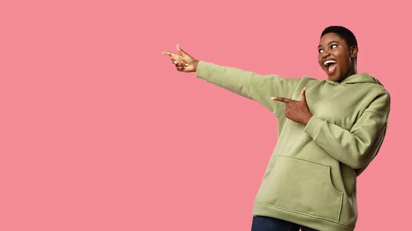 Emocionada dama afroamericana señalando los dedos aparte de fondo rosa —  Fotos de Stock