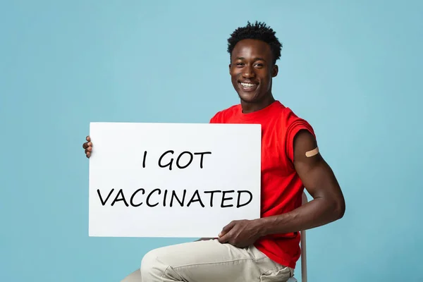 Imunizační kampaň. Šťastný černoch drží plakát s vakcinovaným textem — Stock fotografie