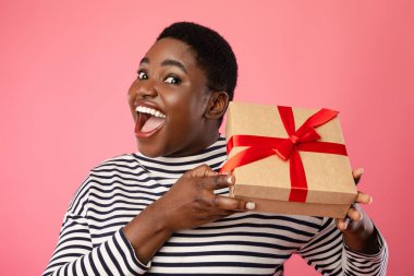 Artı, Pembe Arkaplan Üzerinde Paketlenmiş Hediye Kutusu Tutan Afrikalı Kadın