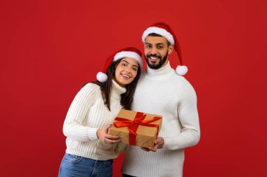 Sevgili Arap eşleri Noel hediyelerini gösteriyorlar, Noel Baba şapkası takıp 2022 yılını birlikte kutluyorlar.