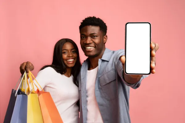 Amar a la pareja negra con compras abrazando y mostrando el teléfono celular, maqueta —  Fotos de Stock