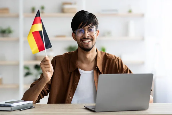 Lachende indiaanse jongen student tonen vlag van Duitsland, met behulp van laptop — Stockfoto