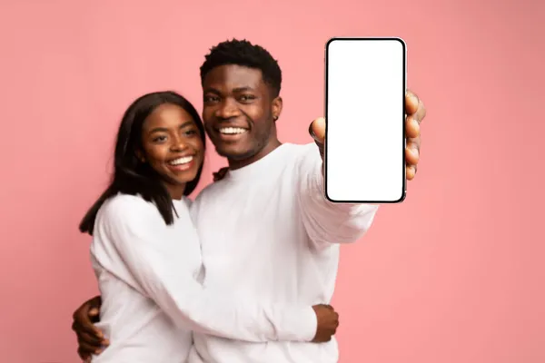 Loving black couple hugging and showing cellphone, mockup — Stok Foto