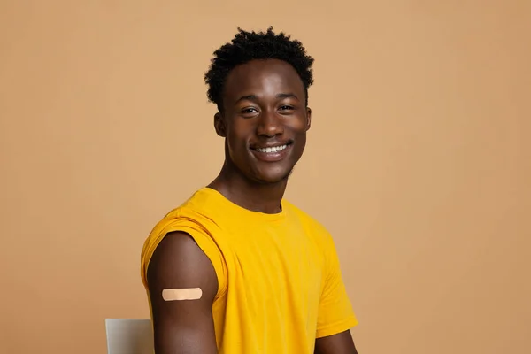 Inmunización contra el Coronavirus. Retrato de tipo negro vacunado con banda adhesiva en el hombro —  Fotos de Stock