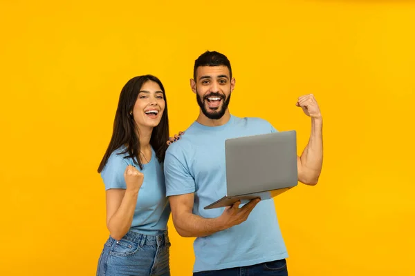 Χαρά arab ζευγάρι κρατώντας φορητό υπολογιστή και γιορτάζει την επιτυχία με σφιγμένες γροθιές, τυχεροί νικητές με PC — Φωτογραφία Αρχείου