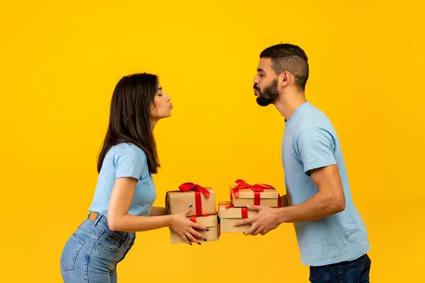 Boční pohled na romantické arabské manžely vyměňovat dárky na Valentýna nebo výročí, snaží se políbit navzájem — Stock fotografie