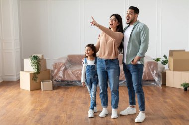 Mutlu Müslüman aile yeni bir daire alıyor, parmakla işaret ediyor.