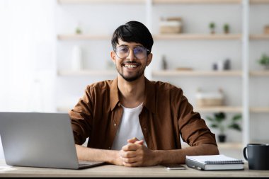 Ofiste dizüstü bilgisayarla çalışan neşeli Hintli girişimci