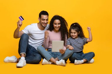 Çevrimiçi satış. Neşeli Orta Doğu Ailesi Dijital Tablet ve Kredi Kartı Kullanıyor