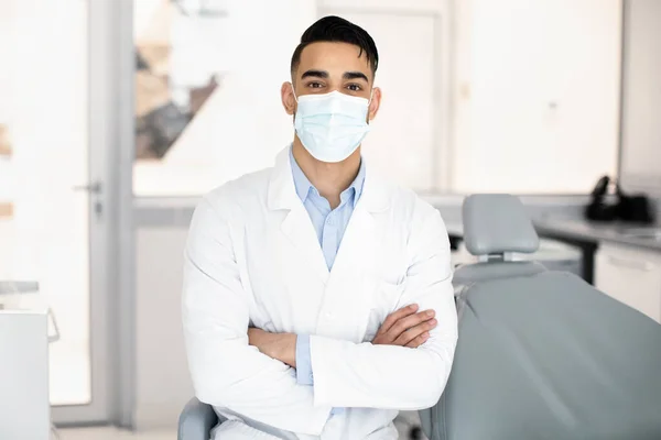 Usługi dentystyczne. Portret przystojnego arabskiego dentysty w mundurze i masce medycznej — Zdjęcie stockowe