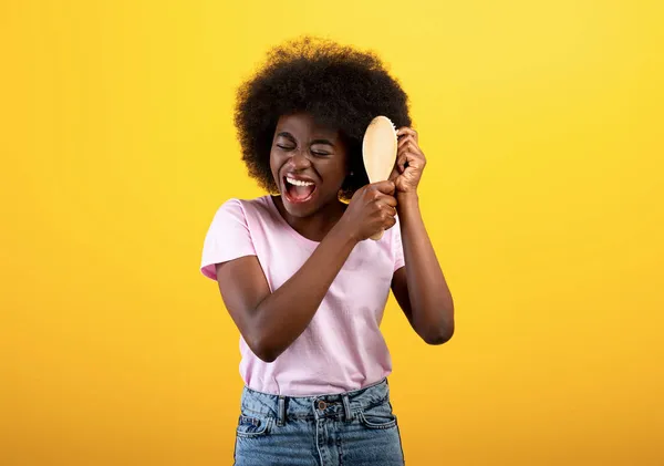 Cabelo a desembaraçar. Africano senhora americana escovar cabelos emaranhados com escova de cabelo, sofrendo de dor, fundo amarelo — Fotografia de Stock
