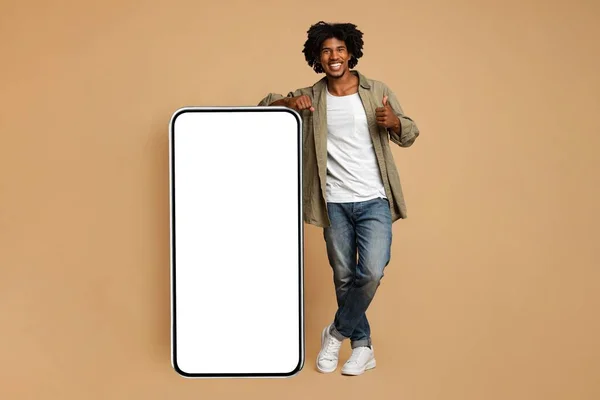 Hnadsome Smiling Black Guy Leaning On Big Smartphone With Blank White Screen — 图库照片