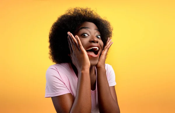 Wow, offerta. Overjoyed afro americano signora guardando fotocamera in eccitazione e toccare il viso su sfondo giallo — Foto Stock