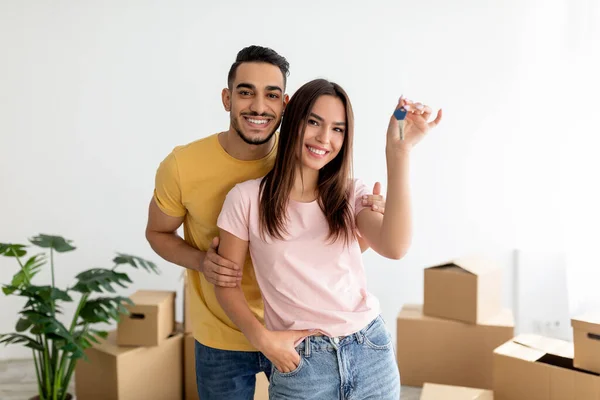 Happy multiracial pár ukazuje klíč od domu, stěhování do nového bytu spolu — Stock fotografie