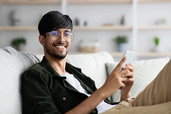 Pozitivní arabský chlap hraje mobilní hry doma — Stock fotografie