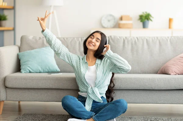 Porträt einer hübschen Inderin mit Kopfhörer, die zu Hause mit geschlossenen Augen Musik hört — Stockfoto