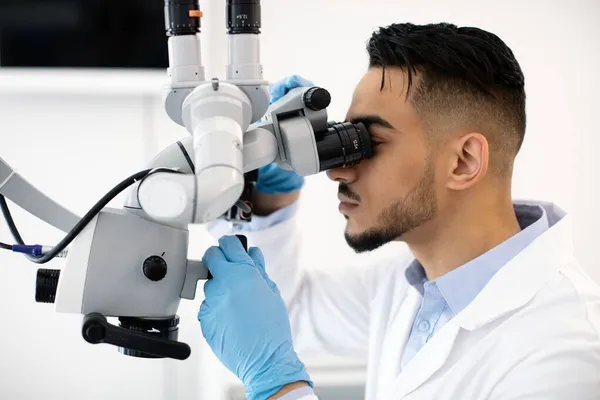 Jonge Arabische tandarts met behulp van tandheelkundige microscoop op het werk in de kliniek — Stockfoto