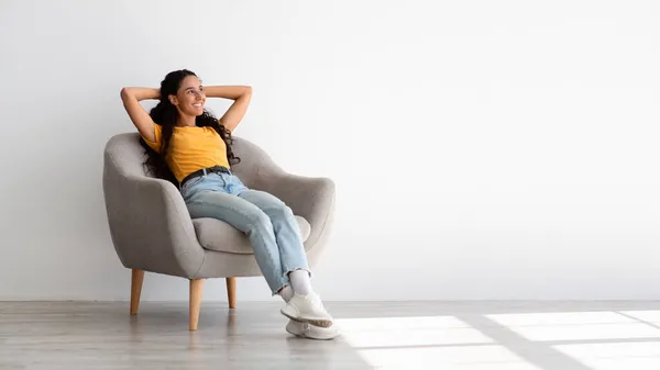 Bella sognante giovane donna rilassante in comoda sedia a casa — Foto Stock