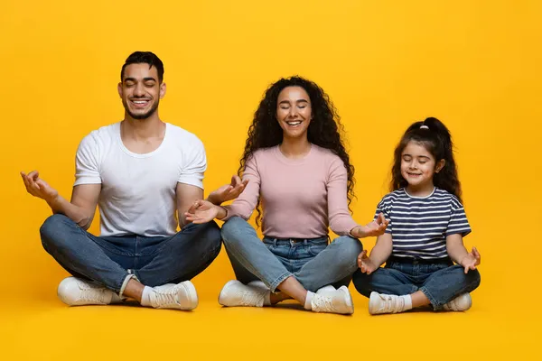 Happy Arab Family Of Three With Little Daughter Meditating Together In Studio