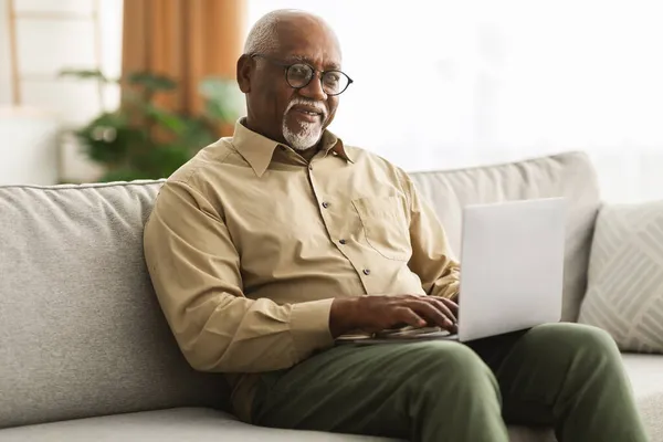 自宅でラップトップコンピュータを使用して笑顔のシニア黒人男性 — ストック写真