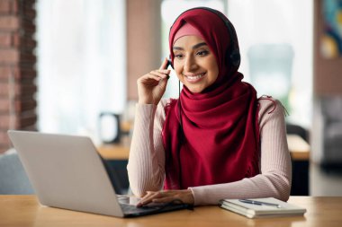 Neşeli Müslüman kadın iş arkadaşlarıyla görüntülü görüşme yapıyor.