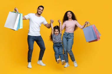 Aile alışverişi. Neşeli Arap Ebeveynler ve Küçük Kız Parlak Alışveriş Çantalarını Tutuyor