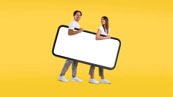 Cara e senhora andando com grande tela de smartphone branco vazio — Fotografia de Stock