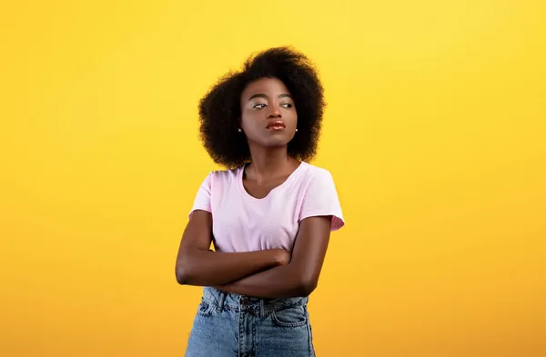 Portrait de dame afro-américaine sérieuse regardant de côté et posant avec les bras croisés sur fond de studio jaune — Photo