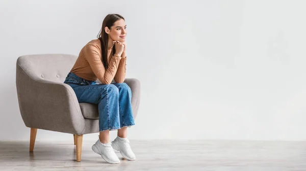 Mujer millennial soñadora mirando el espacio en blanco con expresión facial pensativa contra la pared blanca del estudio, panorama —  Fotos de Stock