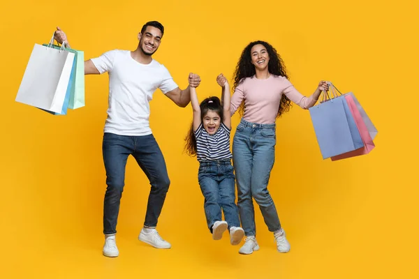 Aile alışverişi. Neşeli Arap Ebeveynler ve Küçük Kız Parlak Alışveriş Çantalarını Tutuyor — Stok fotoğraf