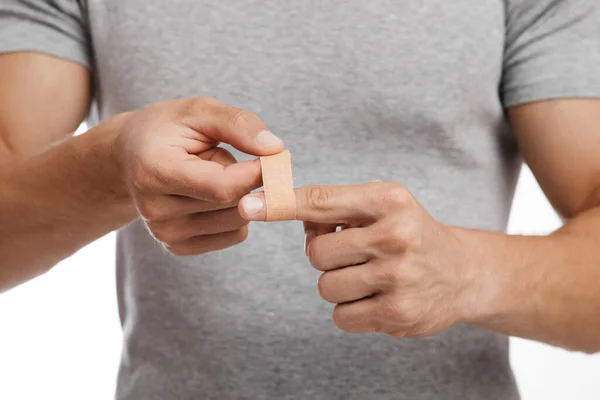 Muscular milenar caucasiano masculino sofrendo de dor no dedo e aplicando band-aid — Fotografia de Stock