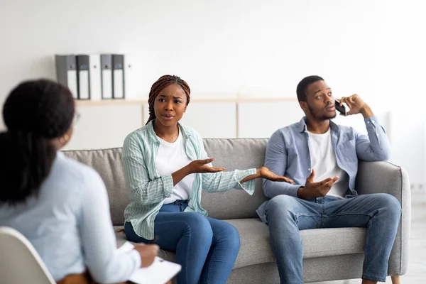 Mujer afroamericana molesta quejándose sobre el abuso de teléfonos inteligentes de sus maridos durante la consulta psicológica — Foto de Stock