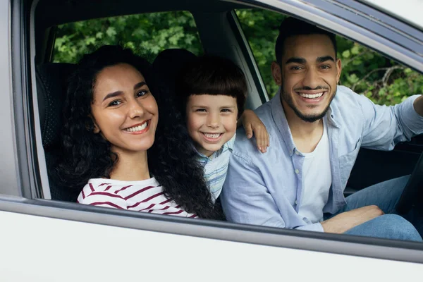 Портрет счастливой арабской семьи верхом на автомобиле вместе, улыбаясь через окно — стоковое фото