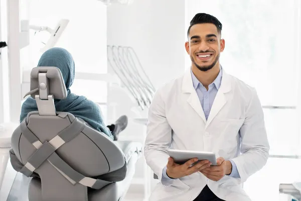 Retrato de bonito médico dentista árabe com tablet digital posando no local de trabalho — Fotografia de Stock