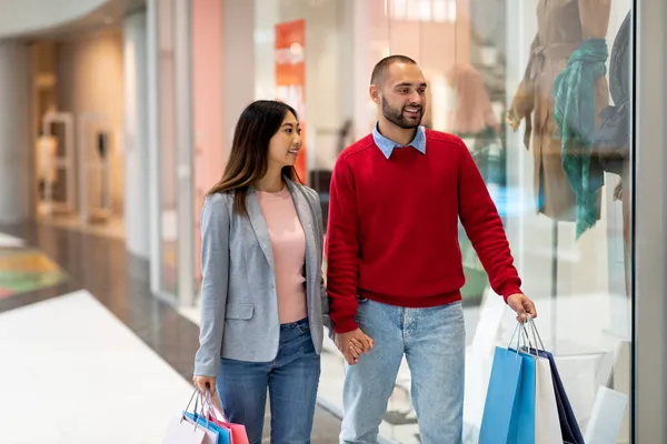 Αγαπώντας διαφυλετικό ζευγάρι περπάτημα κατά μήκος των παραθύρων καταστημάτων, κρατώντας τα χέρια, ψώνια για ρούχα στο εμπορικό κέντρο, αντίγραφο χώρο — Φωτογραφία Αρχείου