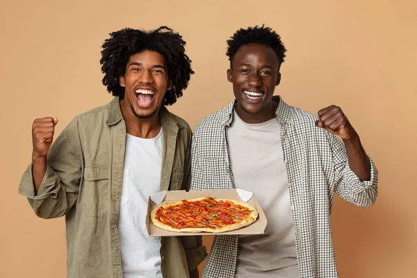 Entrega de alimentos. Dos alegres chicos negros que sostienen la caja con sabrosa pizza —  Fotos de Stock