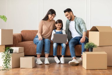 Mutlu erkek kadın ve kız taşındıktan sonra bilgisayar kullanıyor.