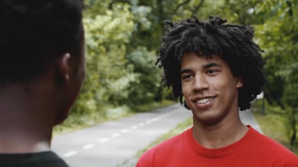 Zwei afroamerikanische Millennial-Männer reden im Park im Freien — Stockvideo