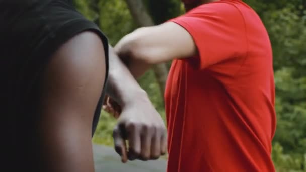 Två svarta killar som knäpper armbågar och pratar stående utomhus, beskurna — Stockvideo