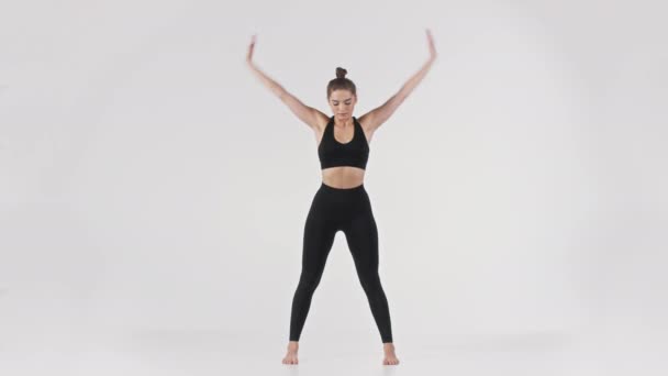 Jeune femme yogi active debout coude vers l'avant, étirant le dos, démontrant la position de yoga Uttanasana — Video