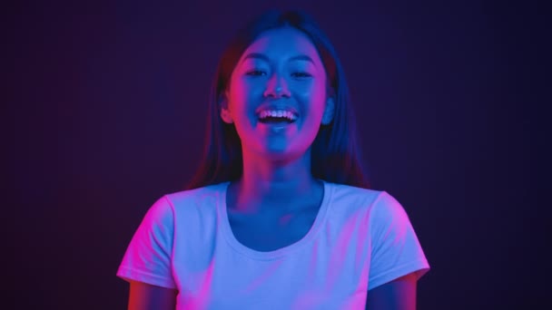 Pura felicidad. Joven mujer coreana feliz riendo a la cámara, sintiéndose positiva y alegre, posando en luces de neón púrpura — Vídeos de Stock