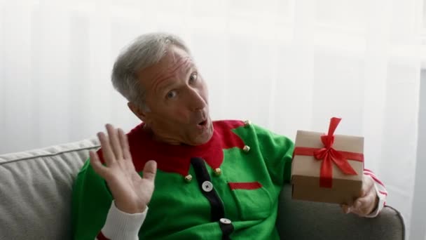 Funny senior man wearing christmas elf costume holding gift, waving at camera — Stock Video © Milkos #522229552 Funny senior man wearing christmas elf costume holding gift, waving at camera — Stock Video © Milkos #522229552