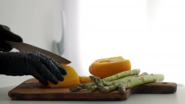 Mutfakta sarı biber ve kuşkonmaz kesen tanınmamış bir aşçı.