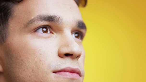 Extreme close up portrait of young inspired caucasian man looking up with delight and smiling, empty space, slow motion — Stock Video