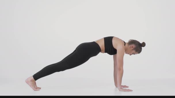 Rugversterkende training. Jonge actieve dame dragen zwarte sport pak oefenen neerwaartse hond pose, stretching haar lichaam — Stockvideo