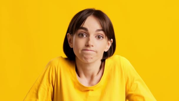 Clueless jong vrouw making schouder Shrug over gele achtergrond — Stockvideo